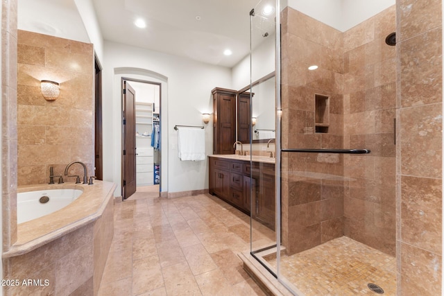 full bath featuring tile patterned floors, a walk in closet, vanity, a shower stall, and a bath