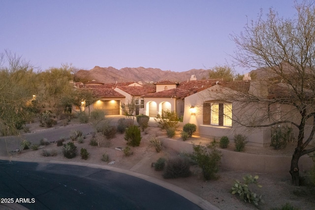 exterior space with a garage, driveway, a tile roof, a mountain view, and stucco siding