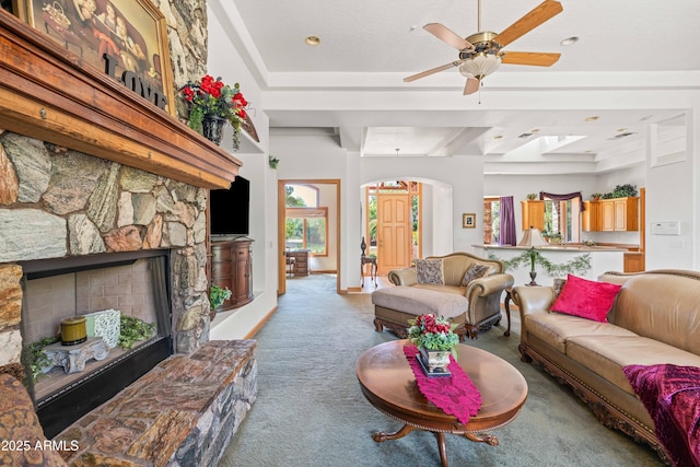 25509 S Lime Dr, Queen Creek, AZ 85142 - carpeted living room featuring arched walkways, a stone fireplace, and ceiling fan