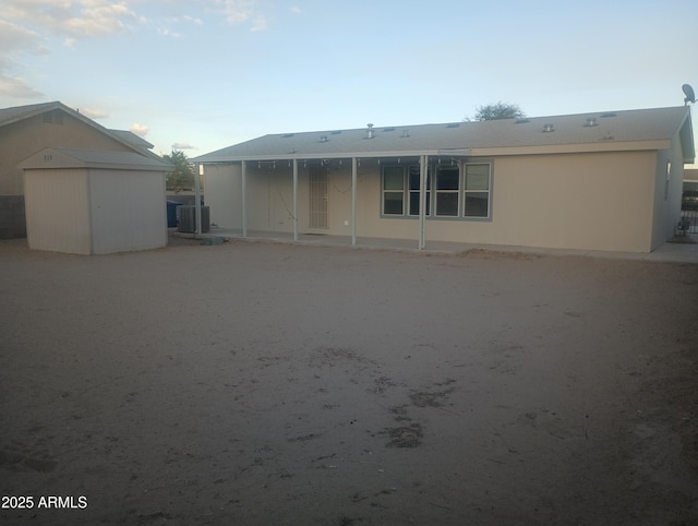 back of property featuring a storage shed and central AC unit