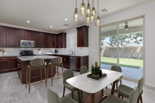 kitchen with decorative backsplash, appliances with stainless steel finishes, a kitchen island, and sink