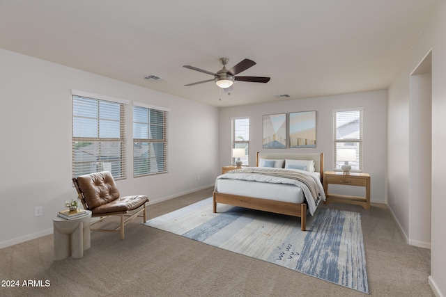 bedroom with ceiling fan, light carpet, and multiple windows