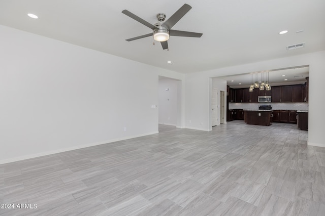 unfurnished living room with ceiling fan with notable chandelier