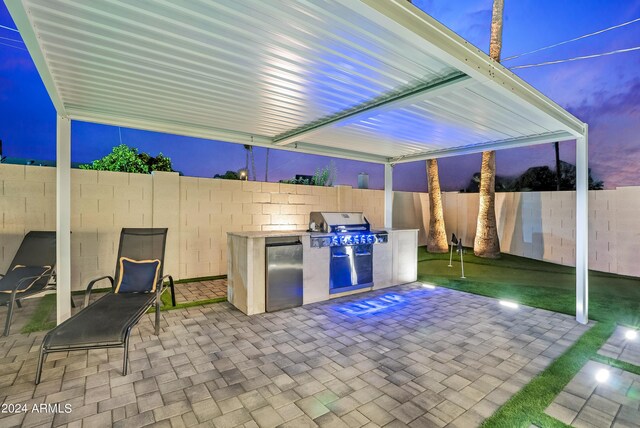 kitchen featuring decorative backsplash, wall chimney exhaust hood, light brown cabinets, stainless steel appliances, and a center island with sink