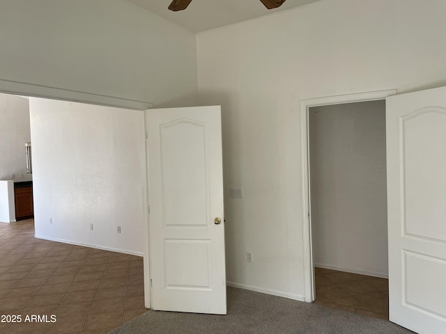 unfurnished bedroom featuring a ceiling fan, dark tile patterned floors, and baseboards