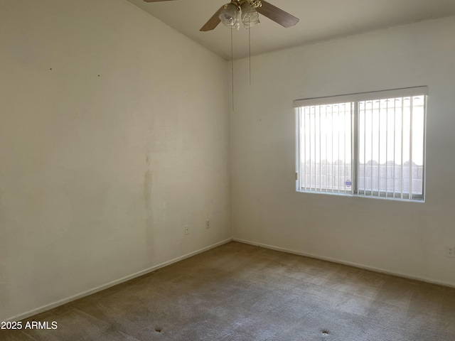 carpeted spare room with a ceiling fan and baseboards