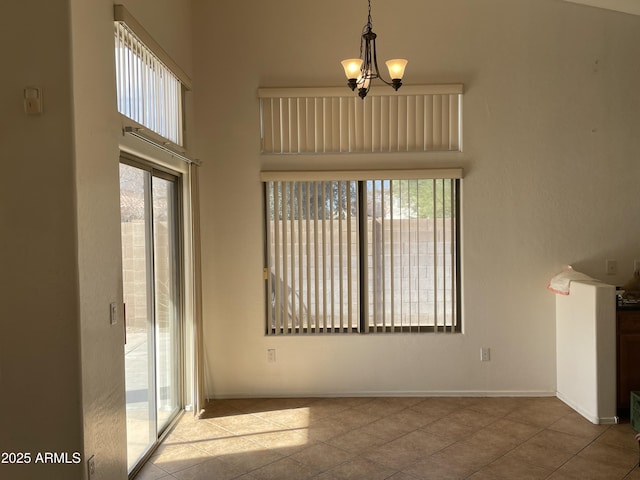 interior space featuring a chandelier, a high ceiling, light tile patterned floors, and baseboards