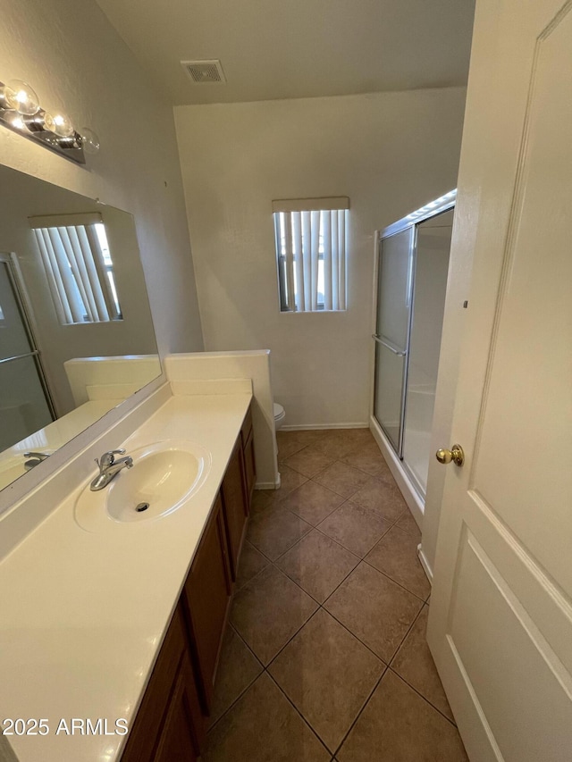 bathroom featuring toilet, vanity, visible vents, a shower stall, and tile patterned floors