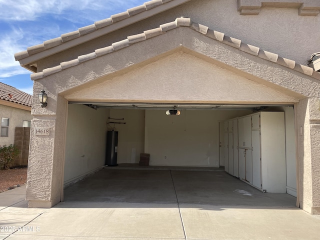 garage with a garage door opener, electric water heater, and driveway