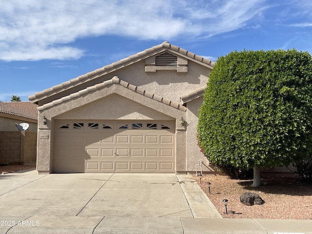 view of front of home featuring a garage, driveway, a tiled roof, and stucco siding