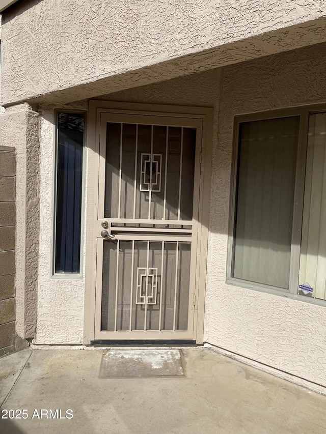 property entrance with a patio and stucco siding