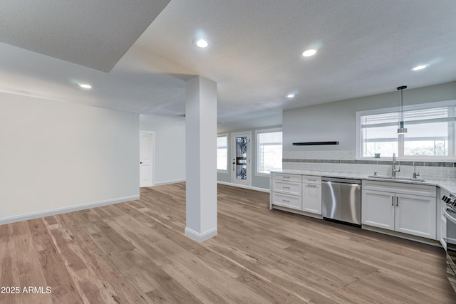 kitchen with a sink, tasteful backsplash, open floor plan, stainless steel appliances, and light wood-style floors