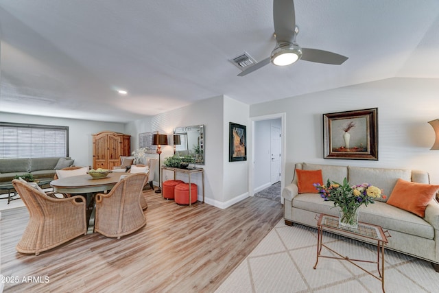 living room featuring a ceiling fan, visible vents, baseboards, lofted ceiling, and light wood-style floors