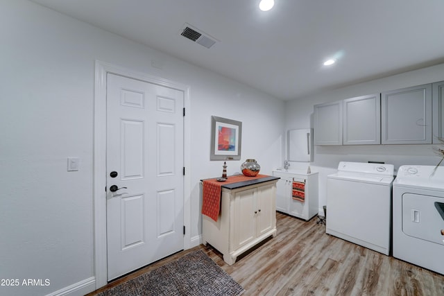 laundry room with visible vents, washer and dryer, cabinet space, light wood-style floors, and baseboards