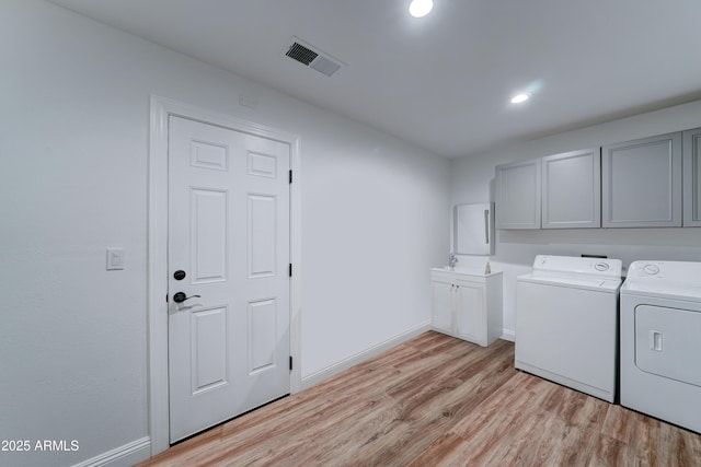 laundry room with visible vents, baseboards, light wood-style flooring, washer and dryer, and cabinet space