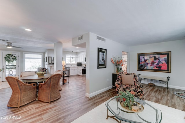 living room featuring visible vents, light wood-style flooring, and baseboards