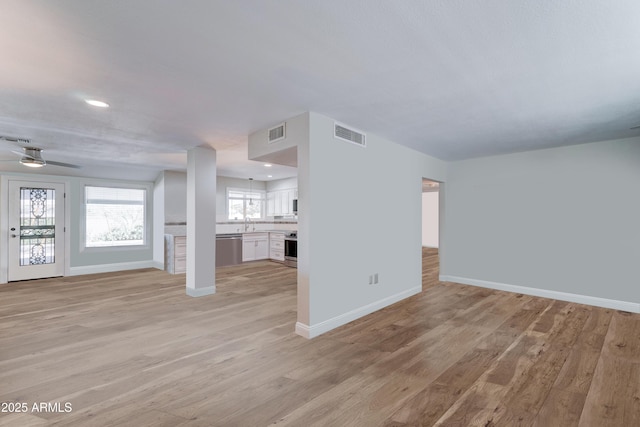 unfurnished living room featuring baseboards, visible vents, and light wood-type flooring