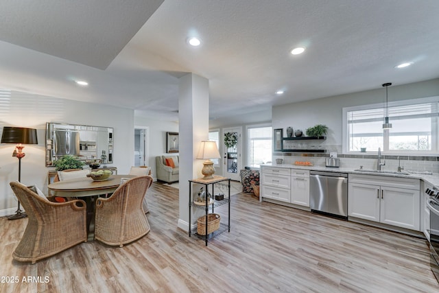 kitchen featuring light wood finished floors, recessed lighting, a sink, dishwasher, and tasteful backsplash