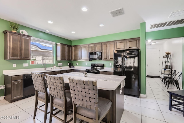 23730 W Hess Ave, Buckeye, AZ 85326 - kitchen featuring black appliances, light countertops, a breakfast bar, a kitchen island, and dark brown cabinetry