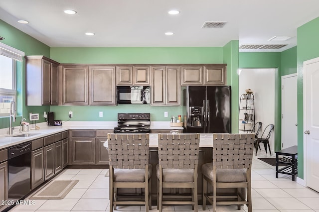 23730 W Hess Ave, Buckeye, AZ 85326 - kitchen with black appliances, a sink, light countertops, a kitchen breakfast bar, and light tile patterned floors