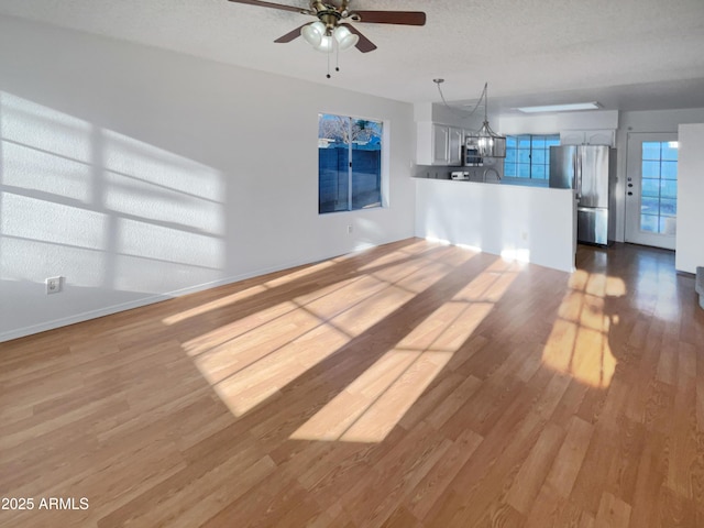 unfurnished living room with ceiling fan, a textured ceiling, and light wood-type flooring