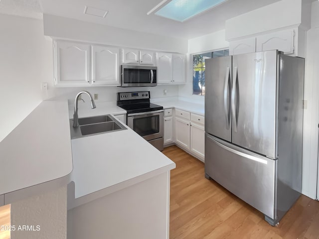 kitchen with white cabinetry, appliances with stainless steel finishes, sink, and light wood-type flooring