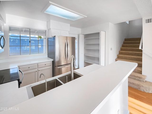 kitchen featuring hardwood / wood-style flooring, stainless steel fridge, and white cabinets