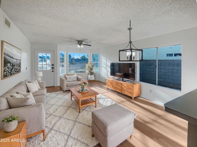 living room featuring a wealth of natural light, a textured ceiling, and light hardwood / wood-style flooring