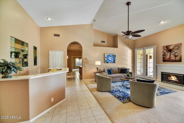 living room with ceiling fan, light tile patterned floors, high vaulted ceiling, and french doors