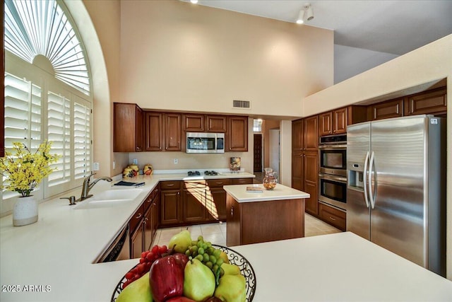 kitchen featuring appliances with stainless steel finishes, a center island, sink, and light tile patterned floors