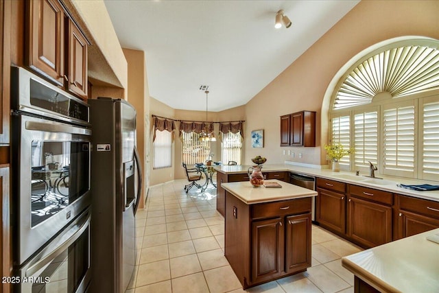 kitchen with pendant lighting, lofted ceiling, sink, light tile patterned floors, and stainless steel appliances