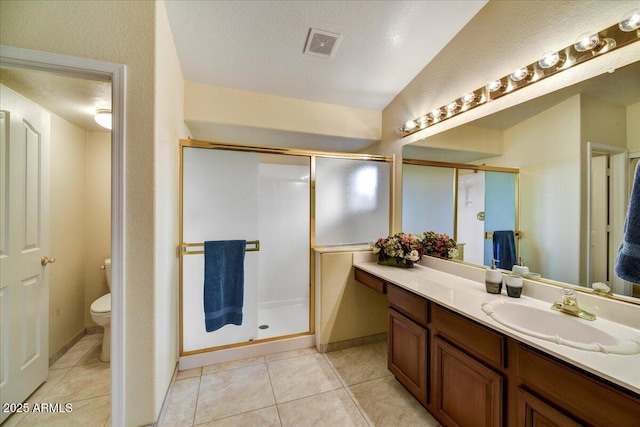 bathroom with vanity, a shower with shower door, tile patterned floors, and toilet