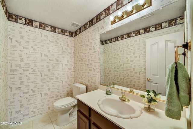 bathroom with tile patterned floors, vanity, toilet, and a textured ceiling