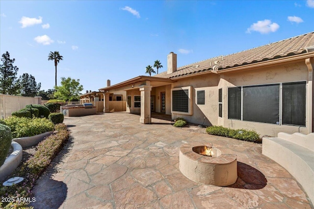 back of property with an outdoor fire pit, a jacuzzi, and a patio area