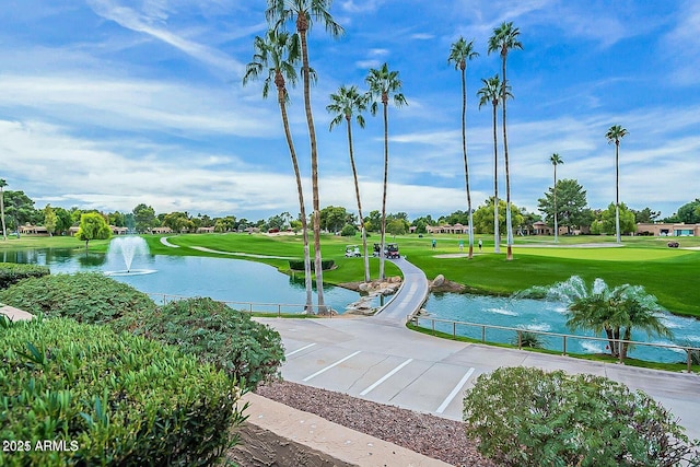 surrounding community with a water view and a lawn