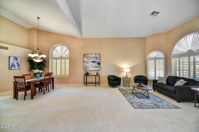 living room with a chandelier, high vaulted ceiling, and light carpet