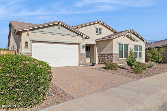 craftsman inspired home with stucco siding, stone siding, an attached garage, and decorative driveway