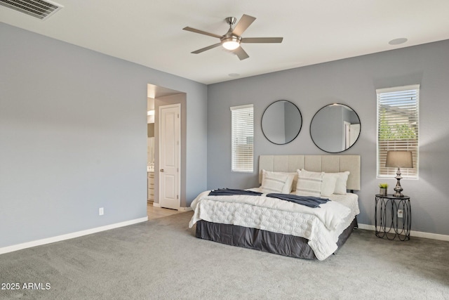 carpeted bedroom with visible vents, ceiling fan, ensuite bath, and baseboards