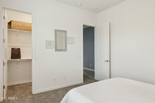 carpeted bedroom with a walk in closet, baseboards, visible vents, and a closet