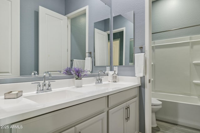 bathroom featuring a sink, toilet, double vanity, and shower / tub combination