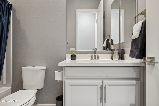 bathroom featuring toilet, vanity, and a textured wall