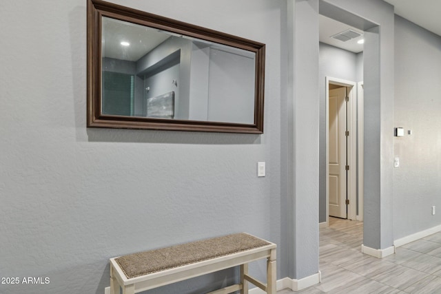 corridor with visible vents, baseboards, and a textured wall