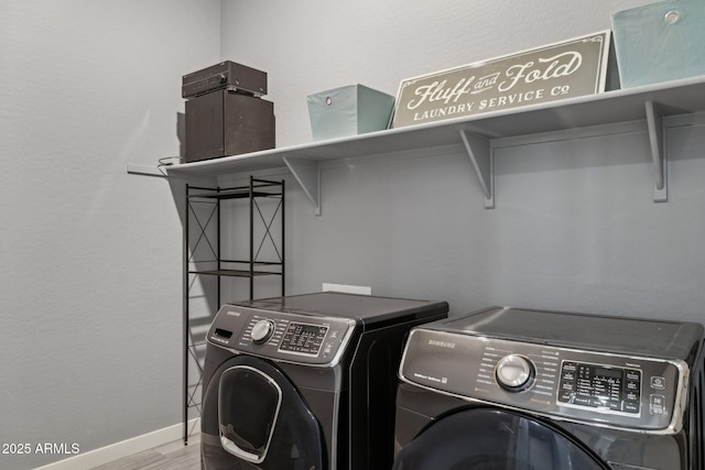 laundry area with baseboards, independent washer and dryer, wood finished floors, and laundry area