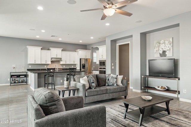 living area featuring visible vents, a ceiling fan, recessed lighting, light wood-style floors, and baseboards