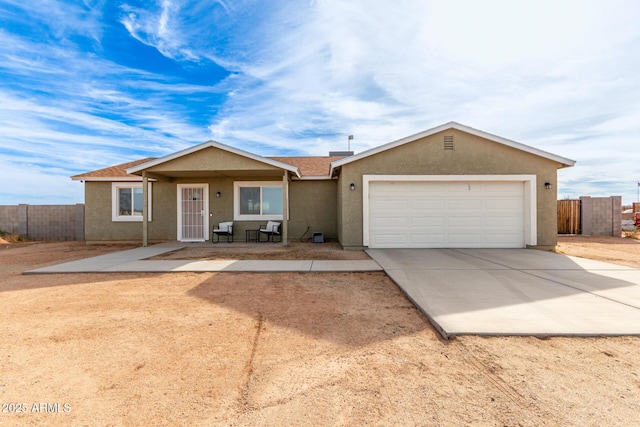 ranch-style house featuring driveway, an attached garage, fence, and stucco siding