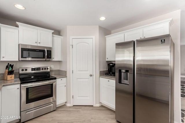 kitchen featuring stainless steel appliances, light wood-type flooring, white cabinets, and light stone countertops