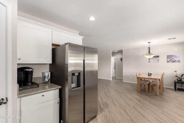 kitchen featuring stainless steel fridge with ice dispenser, hanging light fixtures, light wood-type flooring, white cabinetry, and recessed lighting