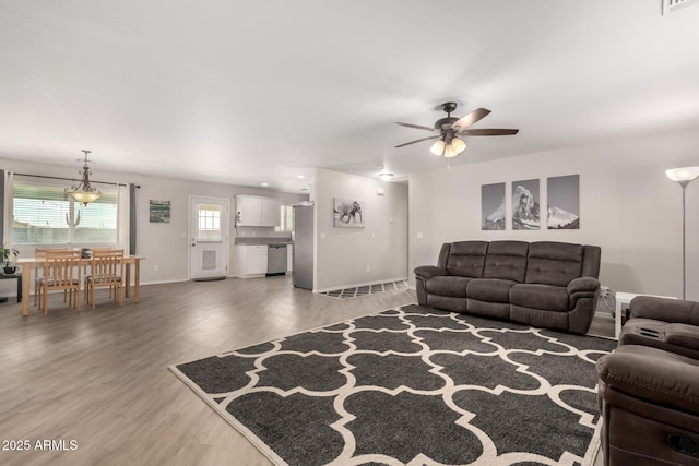 living room with light wood-style floors, visible vents, ceiling fan, and baseboards