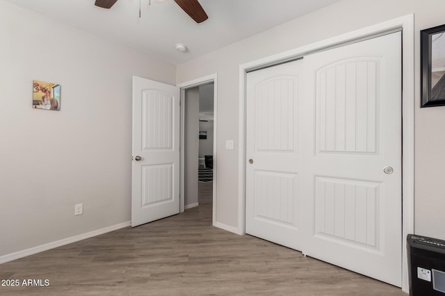 unfurnished bedroom featuring a ceiling fan, a closet, baseboards, and wood finished floors