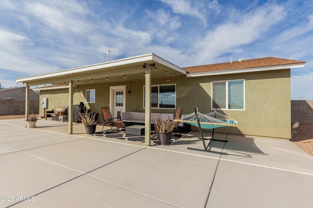 rear view of house with a patio area, fence, an outdoor hangout area, and stucco siding